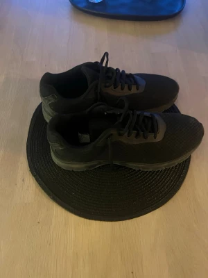 Helt svarta sneakers - Snygga helsvarta sneakers med ovandel i mesh och klassisk snörning. Skorna har en sportig och stilren design med låg profil och gummisula. Perfekta för dig som gillar en clean look och vill ha bekväma skor till vardags.