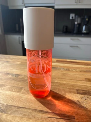 Sol de Janeiro Brazilian Crush 10 - Parfymmist från Sol de Janeiro i en snygg genomskinlig orange flaska med vit kork. Flaskan har en modern, rundad form och är dekorerad med vit text och logga. Perfekt för dig som gillar fräscha och tropiska dofter.