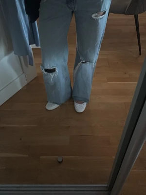 Baggy jeans me hål från Zara - Säljer ett par ljusblå baggy jeans från Zara me hål i. Dom är högbidjade, jag är 162 och går hela vägen ner till marken