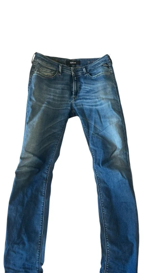 Blå jeans från Replay - Snygga blå jeans från Replay med klassisk femficksdesign och diskreta slitningar framtill. Jeansen har raka ben och normal midja. Perfekta för en avslappnad och trendig look.