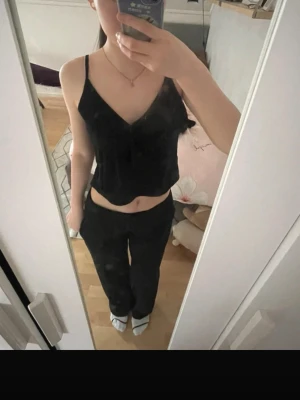 Svart croppad linnetopp - Säljer en svart croppad linnetopp med smala axelband och v-ringad hals. Toppen har en enkel och stilren design som passar perfekt till många olika outfits. Materialet känns lätt och luftigt, vilket gör den skön att bära.