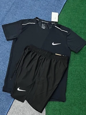 Svart träningsset från Nike - Snyggt svart träningsset från Nike med t-shirt och shorts. T-shirten har vita detaljer vid axlarna och Nike-logga på bröstet. Shortsen har resår i midjan, dragsko och vit Nike-logga på benet. Perfekt för gymmet eller löprundan.