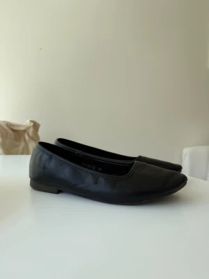Svarta klassiska ballerinaskor - Ett par svarta ballerinaskor med rund tå och låg klack. Skorna har en stilren och enkel design. Väldigt sköna och passar även de med bredare fot. 