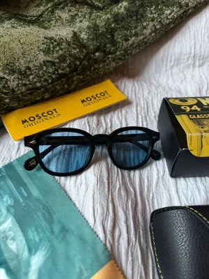 Moscot solglasögon - Snygga svarta solglasögon från Moscot med rundade bågar och klassisk design. Kommer med originalfodral, putsduk och box. Perfekta för dig som vill ha en tidlös och trendig accessoar till sommaren. Helt nytt aldrig använts. 
