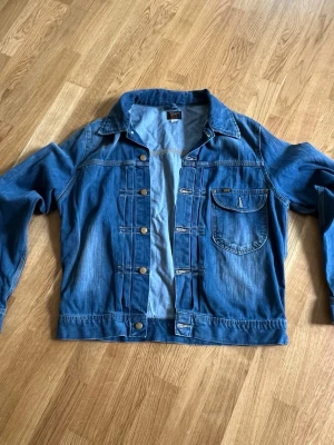 Vintage Lee 101J Jeansjacka XL – Klassisk Blå Denim - Vintage Lee 101J jeansjacka i klassisk blå denim, storlek XL. En av Lees mest ikoniska modeller, känd för sin tidlösa design, slitstarka 100 % bomullsdenim och höga kvalitet. Vintage 101J blir allt svårare att hitta i fint skick. Perfekt för dig som vill ha en äkta klassiker som aldrig går ur mode. Se bilder för skick.
