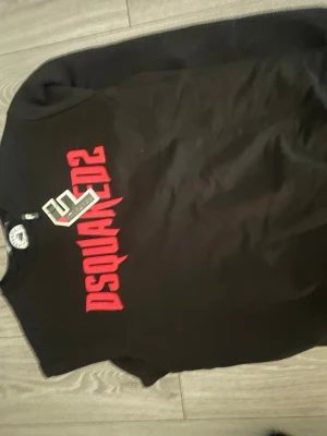 Svart sweatshirt från Dsquared2 - Cool svart sweatshirt från Dsquared2 med stor röd logga tryckt över bröstet. Tröjan har rund halsringning och långa ärmar. Perfekt för dig som gillar streetwear och vill sticka ut med en snygg logga.