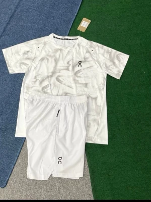 Vit träningsset från On - Säljer ett fräscht vitt träningsset från On med t-shirt och shorts. T-shirten har diskret mönster och logga på bröstet, medan shortsen har elastisk midja, dragkedjeficka och logga på benet. Perfekt för gym eller löpning.