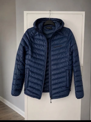 blå dunjacka med huva peak performance  - Hej! Säljer min blå jacka från peak Performance, är u topp skick har en liten skada vid texten som ni ser i bild 3. Köpte för 2399 från deras hemsida säljer endast 300. Perfekt till hösten o vintern som kommer🍂🍁⛄️❄️