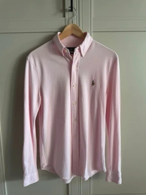 Ralph lauren ljusrosa skjorta - Säljer en klassisk ljusrosa oxfordskjorta från Ralph Lauren. En tidlös modell som passar perfekt till både vardag och lite mer uppklädda tillfällen.  • Storlek: S • Färg: Ljusrosa • Skick: Mycket fint skick • Broderad Ralph Lauren-logga på bröstet • Button down-krage • Perfekt att bära både instoppad och över ett par jeans eller chinos  Obs: Ett litet löst stygn på vänster ärm (se sista bilden). Påverkar varken funktionen eller helhetsintrycket och syns knappt vid användning.  En riktigt snygg o