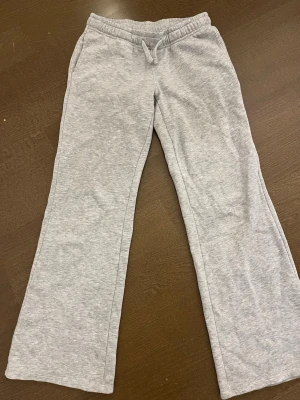 Grå mjukisbyxor från Gina Tricot - Snygga grå mjukisbyxor från Gina Tricot med raka ben och resår i midjan samt dragsko. Byxorna har två sidofickor och är gjorda i mjukt sweatshirtmaterial som är riktigt skönt. Perfekta för chill dagar eller när du vill vara bekväm.