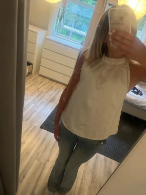 Vit ärmlös halterneck topp Bik Bok - Säljer en stilren vit halterneck topp från Bik Bok i glansigt material. Toppen är ärmlös och har en hög krage som knäpps i nacken. Perfekt till jeans eller kjol för en fräsch look. Säljer för jag råka köpa i fel storlek men aldrig använd 