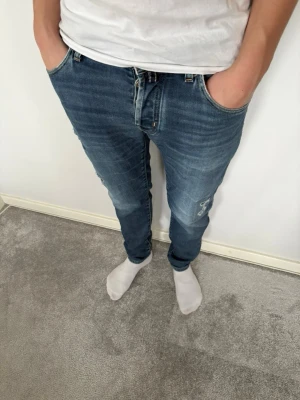 Blå jeans från Jacob Cohën - Snygga blå jeans från Jacob Cohën med slitna detaljer: Modellen är Nick Slim som sitter riktigt bra: Jeansen har ljus tvätt och är tillverkade i Italien med stretchig bomullsdenim för extra komfort: Storkek 30! Fråga mig vid minsta fundering! Nypris runt 5500!