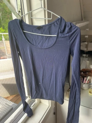 Mörkblå långärmad topp Gina Tricot - En enkel och stilren mörkblå långärmad topp från Gina Tricot. Toppen har rund halsringning och är tillverkad i ett mjukt bomullsmaterial som sitter skönt mot kroppen. Perfekt att matcha med jeans eller kjol för en clean look.