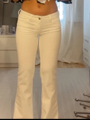 Vita bootcut jeans med hög midja - Säljer ett par vita jeans med bootcut-modell och låg midja. Jeansen har klassisk femficksdesign och stängs med knapp och dragkedja. Materialet är denim med lite stretch för skön passform. Perfekta till en trendig och fräsch look. Köp o jag skickar dem på samma dag
