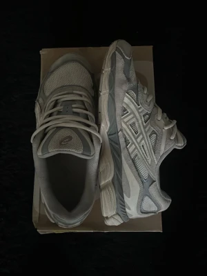 Vita och grå sneakers från Asics, kommer med dubbel snören. - Snygga sneakers från Asics i vitt och grått med klassiska meshpaneler och detaljer i syntetmaterial. Skorna har lågt skaft, snörning och en sportig vibe som passar perfekt till streetwear eller casual outfits.