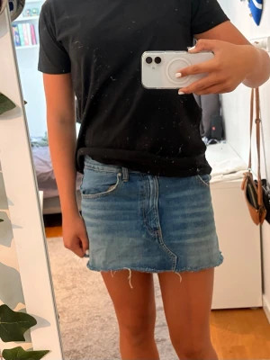 Blå jeanskjol med fransig kant - Snygg blå jeanskjol i klassisk modell.