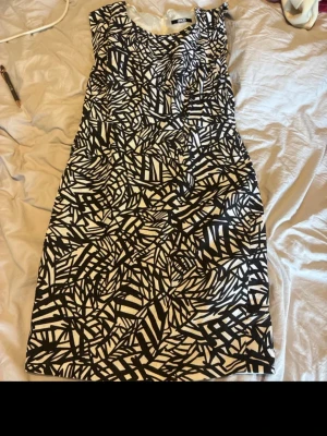Svartvit mönstrad klänning från ASOS - Säljer en svartvit kortklänning från ASOS med grafiskt mönster. Klänningen har rund halsringning och dragkedja i ryggen. Perfekt för dig som gillar statement-plagg med unik design.