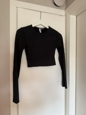 Svart ribbad croppad träningstopp H&M Divided - Svart långärmad träningstopp från h&m, storlek s men kort och liten så skulle säga xs. 