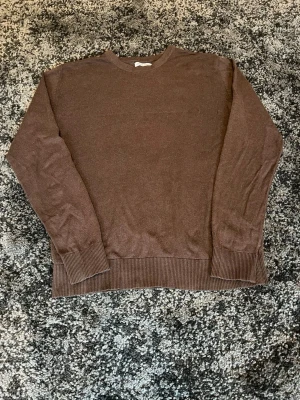 Brun stickad tröja från Jack&Jones  - En stilren brun stickad tröja med rund hals och långa ärmar. Tröjan har breda ribbade muddar vid ärmslut och nederkant för en snygg passform. Perfekt för lager-på-lager och enkel att matcha.