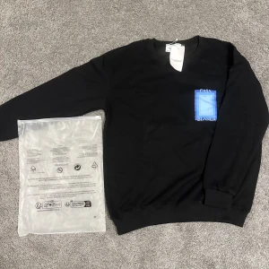 Svart sweatshirt från Casablanca M - Svart sweatshirt från Casablanca med blått grafiskt tryck och texten 'Casa Blanca' på bröstet och ryggen. Tröjan har rund hals, långa ärmar och är tillverkad i mjuk bomull. Perfekt för en clean och stilren look.