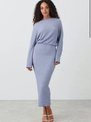 Ljusblå långklänning med ribbad struktur - Snygg ljuslila långklänning med ribbad struktur och långärmad design. Klänningen har en kroppsnära passform och är tillverkad i ett mjukt, stretchigt material som ger en bekväm och stilren look. Perfekt för dig som gillar minimalistiska och trendiga plagg.