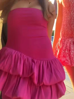 Rosa axelbandslös volangklänning - Snygg axelbandslös kort klänning i stark rosa färg med flera lager volanger nedtill. Klänningen har en figurnära passform upptill och är perfekt för dig som vill sticka ut. Tillverkad i ett mjukt och stretchigt material. ( Aldrig använt)