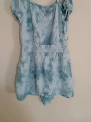 Ljusblå kortklänning med volang - Söt ljusblå kortklänning med volangdetaljer och mjukt, luftigt tyg. Klänningen har korta ärmar och markerad midja som ger en feminin siluett och den har fickor. Perfekt för varma dagar och somriga tillfällen.