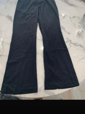 Svarta bootcut kostymbyxor  - Säljer ett par svarta kostymbyxor med bootcut-modell. De har hög midja och är tillverkade i ett stretchigt material som sitter skönt på kroppen. Perfekta för dig som gillar en enkel men trendig look.