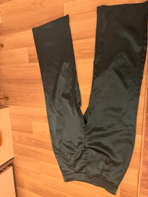 Mörkgröna linnebyxor från SHEIN - Mörkgröna linnebyxor från SHEIN med rak passform och hög midja. Byxorna har en slät yta och är tillverkade i ett lätt och luftigt linnematerial, perfekta för en avslappnad och trendig stil.