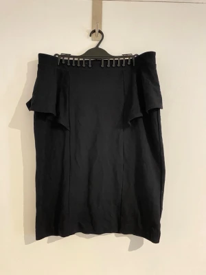 Soaked in luxury Svart Kjol med volangdetalj - Säljer en svart kjol med snygg volangdetalj upptill. Kjolen har en figurnära passform och är perfekt för dig som gillar en stilren look. Dragkedja bak för enkel påklädning. Passar till många olika stilar och tillfällen. Nypris är ca 400 och upp. Använd men väldigt varsamt.