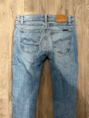 Nudie Jeans Blå W29/L30 - Skinny/Slim Fit - Mycket fint skick. Mått - Midja: 38cm, Ytterbenslängd: 99cm, Benöppning: 14,5cm. Modellen är 185cm & 63kg. Hör av dig vid funderingar!🤝