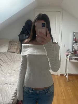 Off shoulder ribbad tröja i beige - Trendig off shoulder tröja i beige med ribbad struktur och långa ärmar. Perfekt för dig som vill ha en snygg och stilren look. Materialet är mjukt och följsamt, vilket gör den bekväm att bära. Passar till jeans eller kjol för en cool outfit.