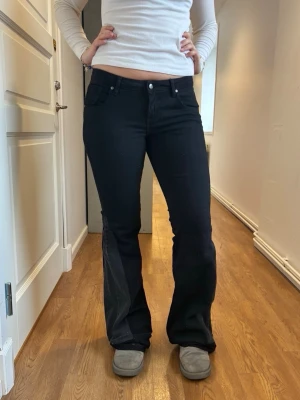 Svarta jeans med spets - Dessa kolsvarta jeans är lågmidjade och har en mörkgrå kil samt svart spets nertill🙌De är bootcut och lite stretchiga💙Måtten är: innerbenslängd - 95 cm, midja 80 cm och lårvidd - ca 48 cm😇. Skulle säga att de passar både M och L men testa mäta måtten ovan för att vara säkra på att de passar!!