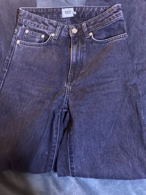 Mörk grå raka jeans från 157 - Säljer ett par gråa jeans från 157 med raka ben och klassisk femficksmodell. Jeansen har hög midja, silverfärgade nitar och kontrastsömmar. Materialet är kraftig denim i bomull som ger en tidlös look. Fråga bara om det är nått eller om du vill ha fler bilder💕