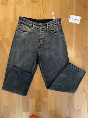 Grå jeans från Acne Studios - Säljer ett par gråa jeans från Acne Studios med klassisk femficksdesign och raka ben. Jeansen har en snygg tvättad look och är tillverkade i bomull. Perfekt för dig som gillar stilrena jeans. Storlek 29x32