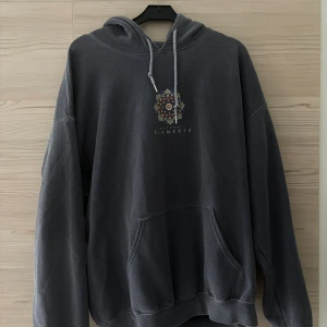Mörkgrå vintage hoodie  - Mörkgrå vintage hoodie, urtvättad färg med större print på ryggen och mindre tryck framtill. Mer åt en loose fit på hoodien. Väldigt gott skick.