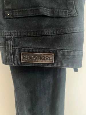 Svarta jeans från Dsquared2 - Snygga svarta jeans från Dsquared2 med klassisk femficksmodell och diskret logga på bakfickan. Jeansen har raka ben och är tillverkade i slitstark denim med en mörk tvätt. Perfekta för dig som gillar stilrena och trendiga plagg.