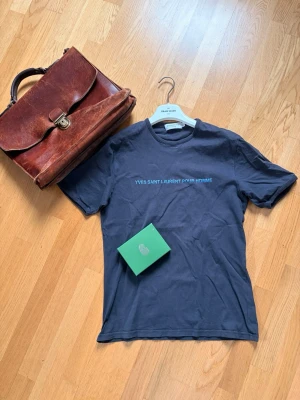 Yves Saint Laurent T-shirt - Säljer nu en grå T-shirt från Yves Saint Laurent med havsblå text längs bröstet✅Tröjan är mycket sällsynt och säljs inte längre🤩Nypris: 4499 Mitt pris: 789👍 Var inte rädd för att ställa fler frågor❤️