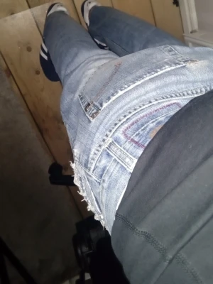 Ljusblå slitna jeans med råa kanter - Säljer ett par ljusblå jeans med slitningar och råa kanter vid fickorna. Jeansen har en klassisk femficksmodell och smal passform. Perfekta för en avslappnad och trendig look. Materialet är denim i bomull.