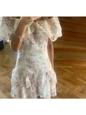 Blommig spetsklänning med volang - Säljer denna såå fina och populära klänningen ifrån fetisch suances. Den är i storlek XS och är 66cm lång och 32cm rakt över midjan🥰Använd två gånger, därav ny skick. Kom privat vid frågor!!❤️