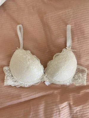 Vit spets BH - Snygg vit BH med mycket spets detaljer. Vet inte vart den är ifrån med den är inte använd och är i storlek 70A men jag skulle säga att den upplevs något större.