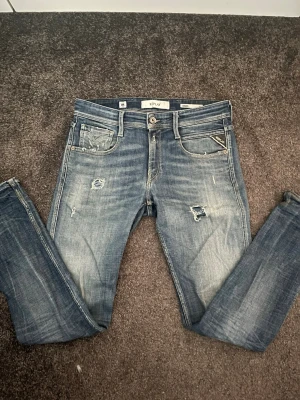 Replay Anbass - Replay Anbass aged 05 jeans med snygga slitningar. Skicket som ny, inga defekter. Storlek 28/32. Mitt pris endast 595kr. 