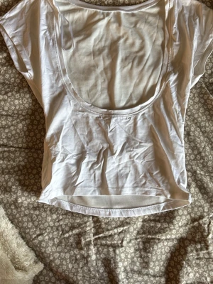 Vit topp med djup rygg från bikbok  - Säljer en vit croppad topp med korta ärmar och en riktigt djup, öppen rygg. Perfekt för dig som gillar en enkel men ändå snygg stil. Gjord i mjuk bomull som känns skön mot huden. Passformen är tight och toppen är enkel att matcha med jeans eller kjol. 💘