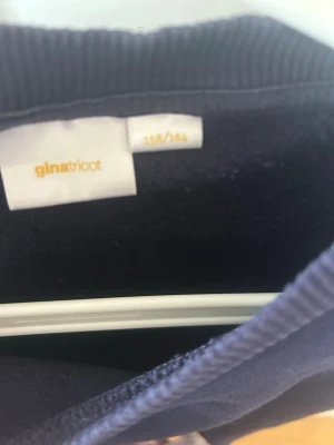 Mörkblå topp med puffärm Gina Tricot - En mörkblå topp från Gina Tricot med rund hals och puffade korta ärmar. Toppen har ribbad kant vid halsen och nederkanten, vilket ger en snygg och modern look. Perfekt för dig som gillar stilrena plagg med en twist.