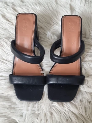Svarta sandaler med bred klack, storlek 39 - Stilrena svarta sandaler från ASOS med två breda remmar och fyrkantig tå. Sandalerna har en chunky blockklack och en innersula i beige läder-look. Perfekta för dig som gillar minimalistisk design och komfort.
