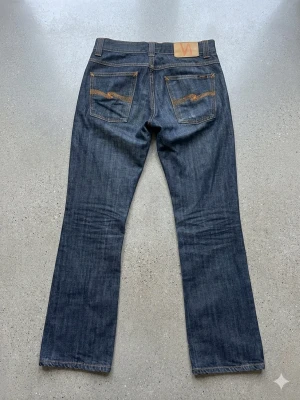 Vintage Archive Nudie Bootcut Ola - 🔥 Säljer dessa sjukt feta Vintage Raw Denim Bootcut Ola (2005). Uppskattas till Storlek 29/30. Otroligt sällsynta och har en snygg eftertraktad passform. Chans till att skapa sjuka fades finns! Se mått nedan 👇🏼 Midja: 37 cm Ytterbenslängd: 99–100 cm Benöppning: 21 cm ⚠️ Bra att veta innan köp * Jag gör ej returer ⛔️ * Eftersom att varan är begagnad så kan det finnas defekter som jag missat (tex fläckar) ✅ * Köp helst med PostNord leverans‼️ * Mått kan ha en felmarginal på 1–2 cm.