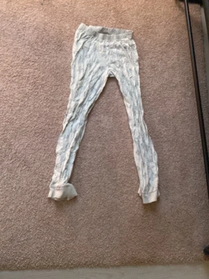 Grå pyjamasbyxor med tecknade figurer - Mysiga grå pyjamasbyxor med elastisk midja och tryck av söta tecknade ansikten över hela tyget. Byxorna har muddar vid bensluten och är perfekta för chill hemma. Materialet känns mjukt och bekvämt mot huden.