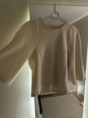 Topp från Gina Tricot - Säljer denna fina beiga topp från Gina, den är tajt på midjan och lös på armarna. Den är i stl L, Inga defekter och oanvänd då jag har shoppingberoende😅 Väldigt rik och fint matrial.