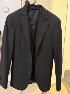 Svart kostymkavaj Dressmann Extra Slim - Snygg svart kostymkavaj från Dressmann i extra slim fit-modell. Kavaj, väst och byxor ingår. Använd en gång.