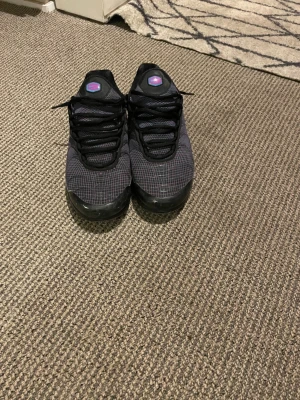 Svarta sneakers med rutmönster - Säljer ett par Lila/blåa Nike Tns.De är små på mig bra material och fina.